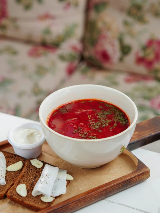 a plate with bread, yogurt and a red soup in a bowl