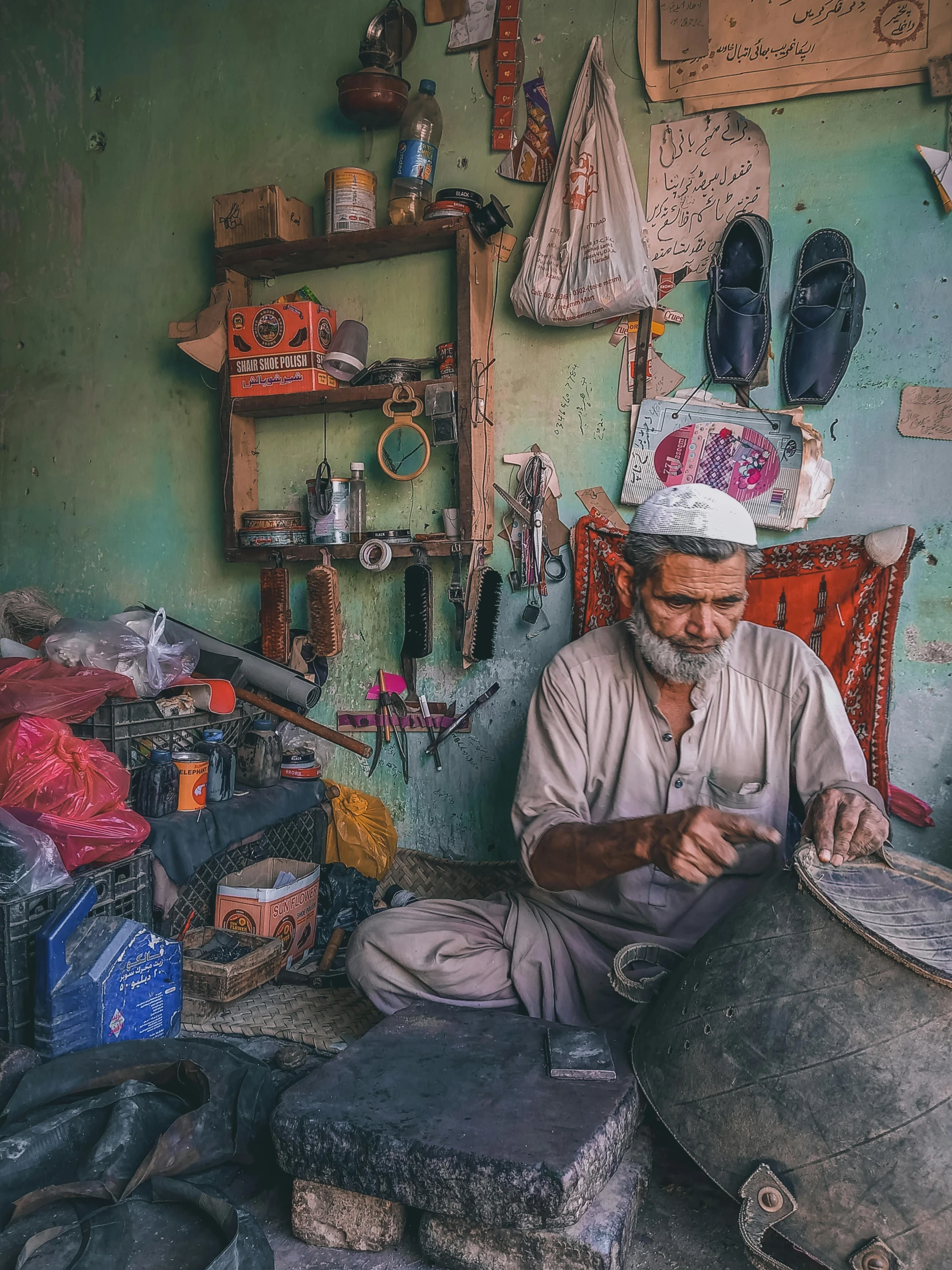 an old man sitting on the floor with several items around him