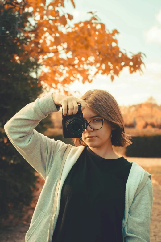 a woman wearing glasses holding up a camera