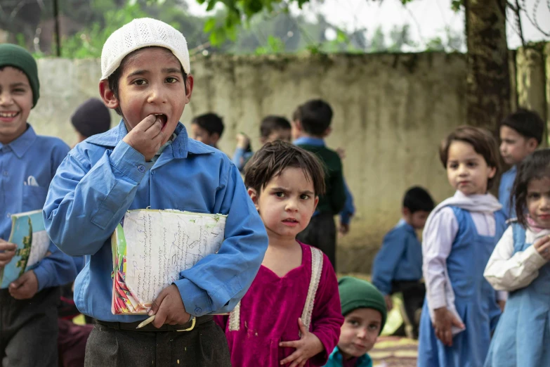 three s stand together in the foreground with children holding books behind them