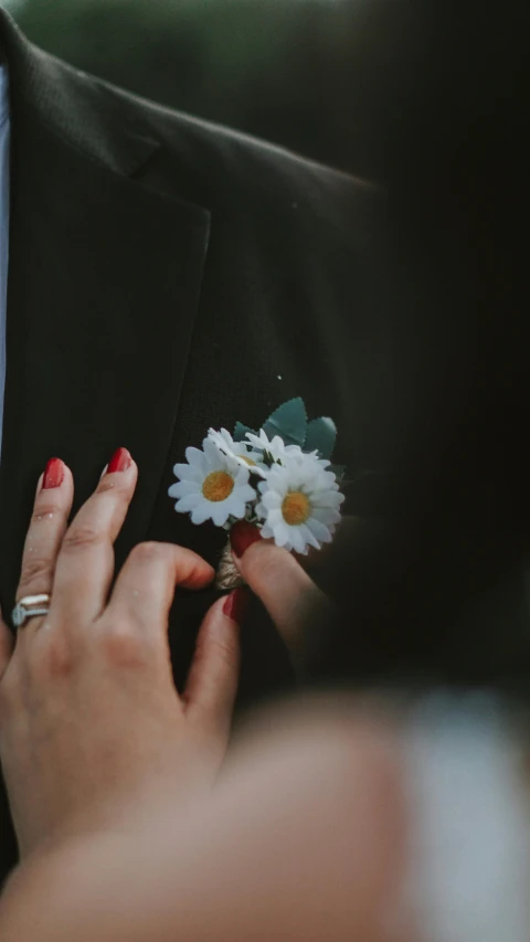 a person wearing a suit holding a flower