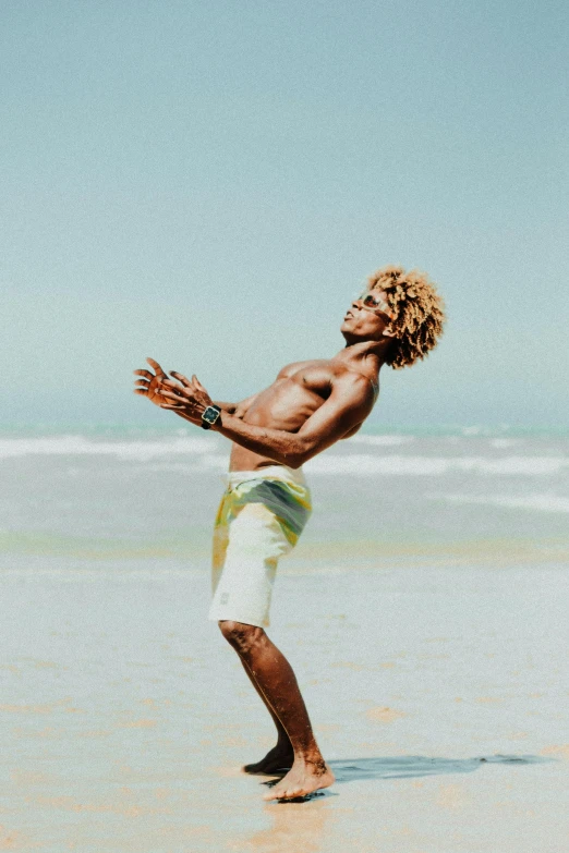 a young man playing with a ball on the beach