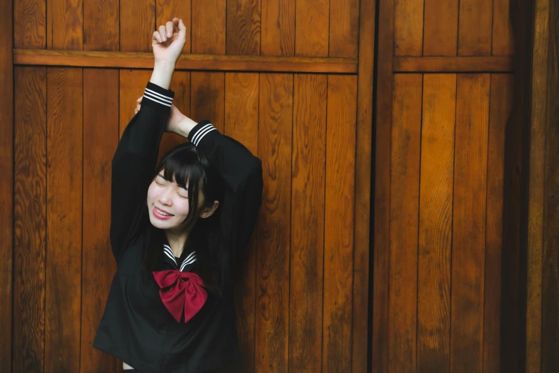 a woman wearing a black outfit standing next to a wooden wall