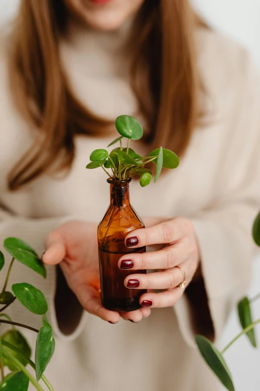 a woman is holding a bottle with plants inside