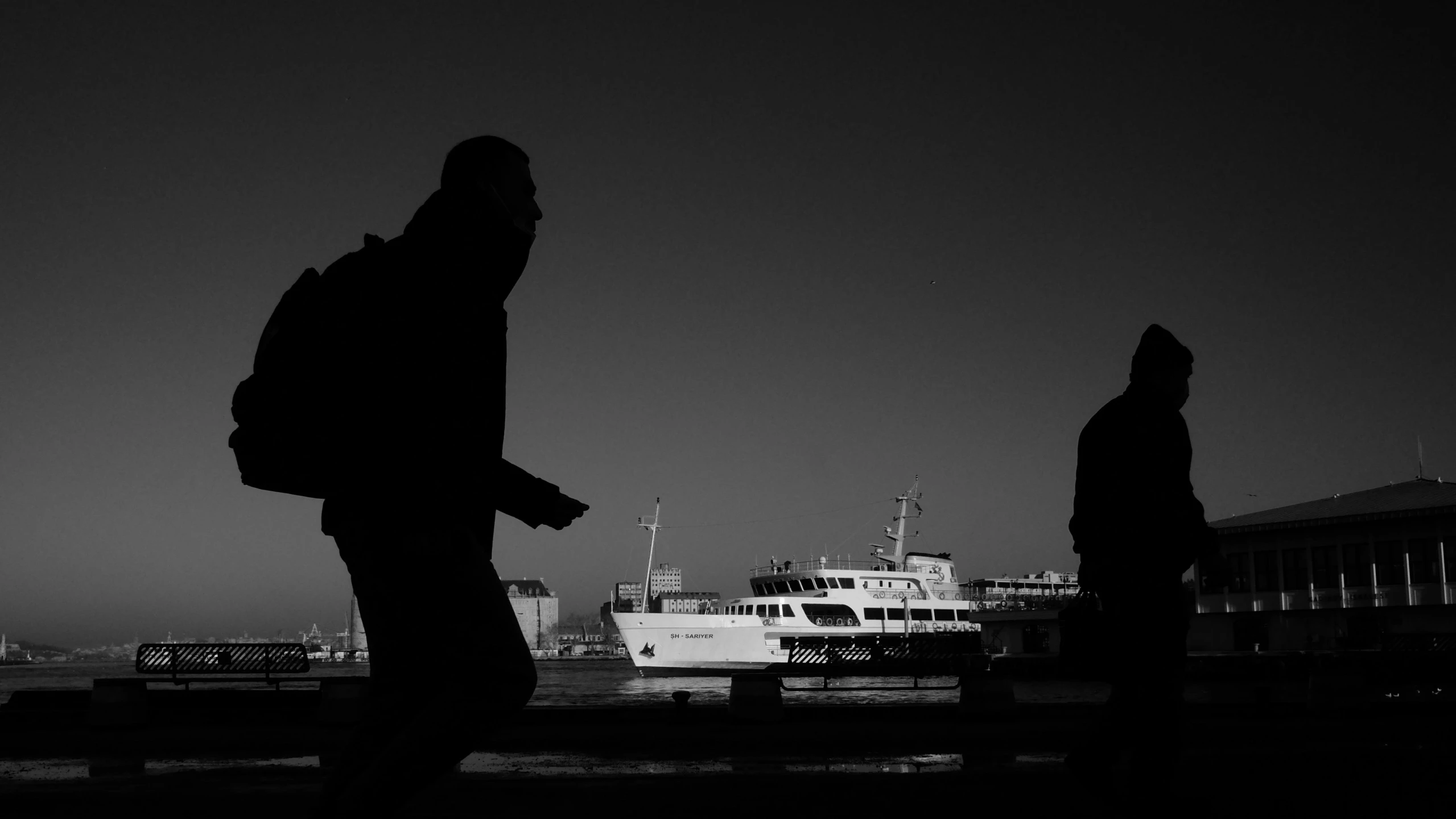 silhouette of two people looking at a large ship