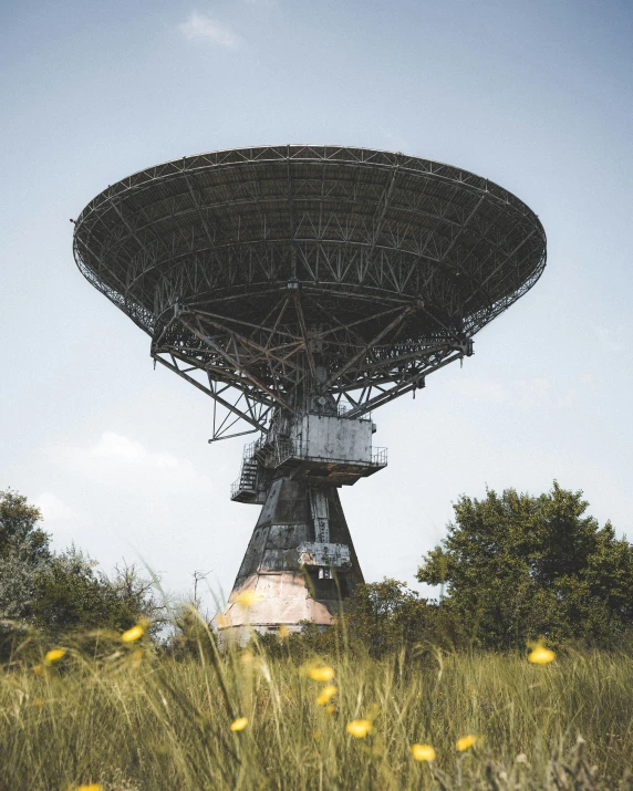 a satellite dish sitting on top of a large grass covered field