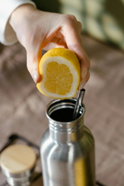 someone holding a lemon in a metal jar