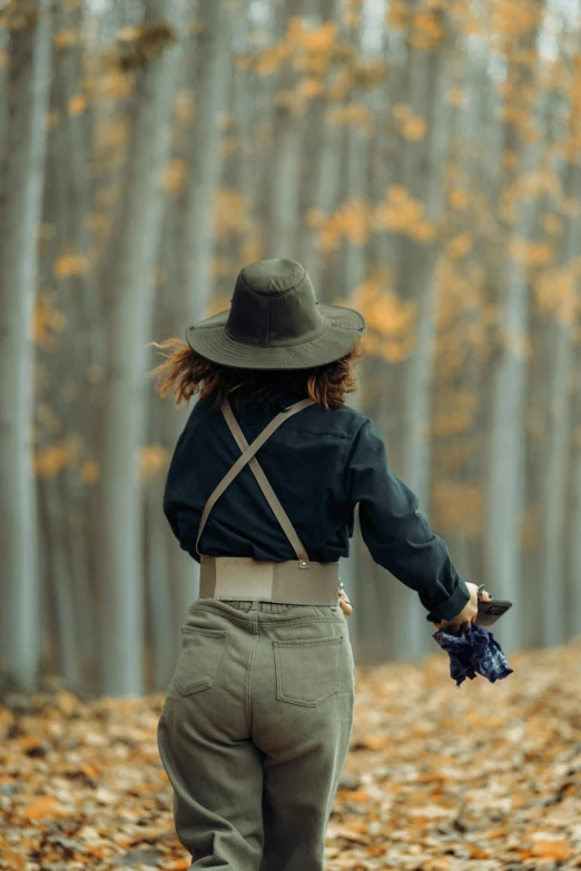 a young woman walking in the woods with leaves in her hand