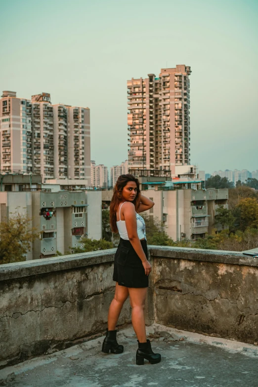 a woman in a short black skirt poses on a rooftop