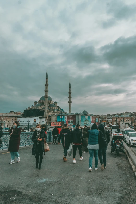 a group of people walking across a street next to a tall building