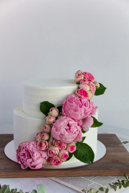 a close - up of a four tiered white cake with flowers on top