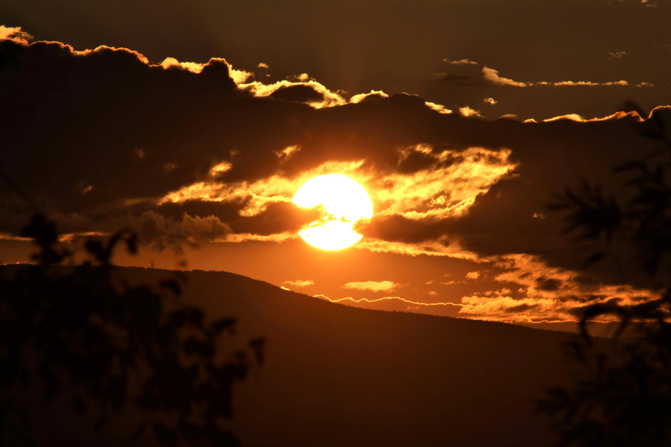 the sun is setting in a cloudy sky