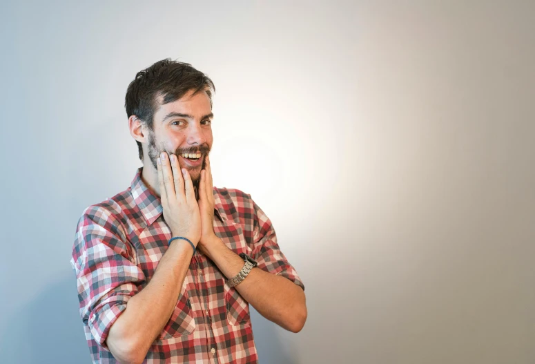 a man in a plaid shirt smiles while talking on a phone