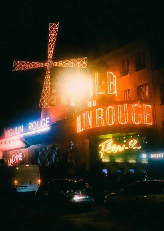 traffic traveling down a city street at night under lit signs