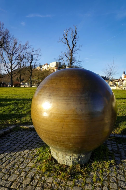 a large round metal object sitting in the middle of a park