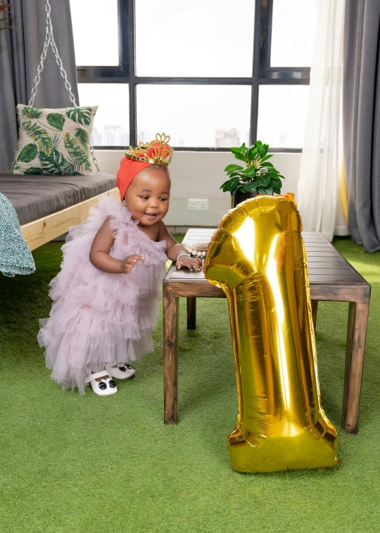 an adorable baby sitting on a table with a balloon