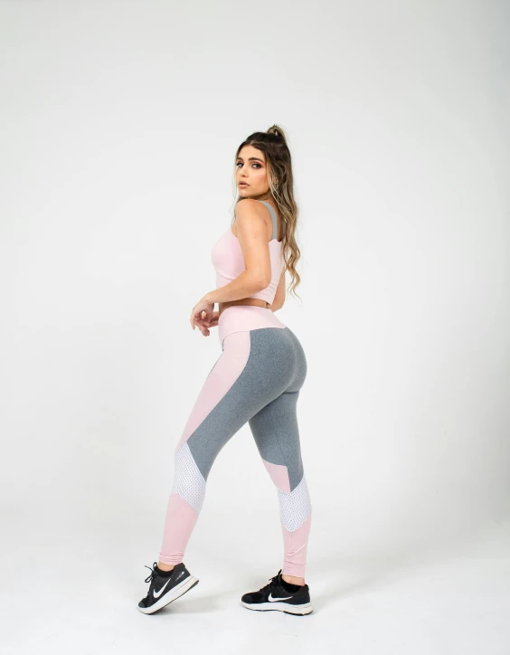 a woman is posing in her pink and grey sports suit