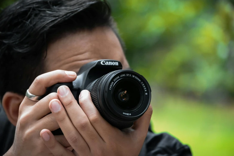 a man holding a digital camera next to his face