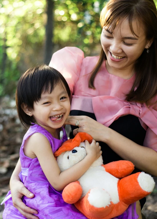 a little girl is holding a stuffed animal in the forest