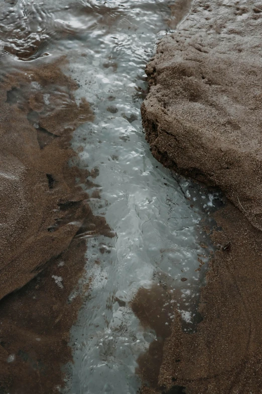 closeup of water in shallow channel between sand and beach