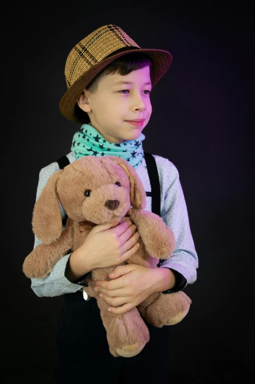 the boy is holding a teddy bear and wearing a hat