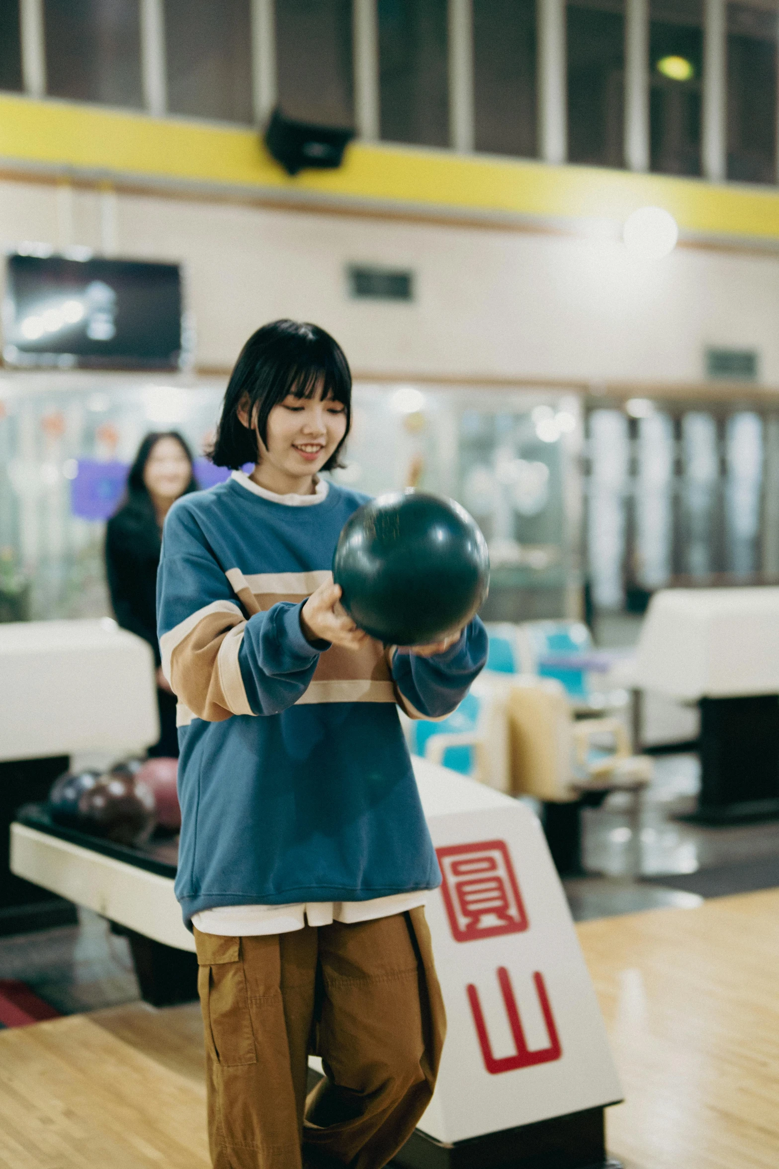 the girl smiles as she holds a bowling ball