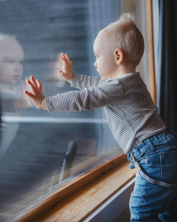 a little baby looking out the window at a person