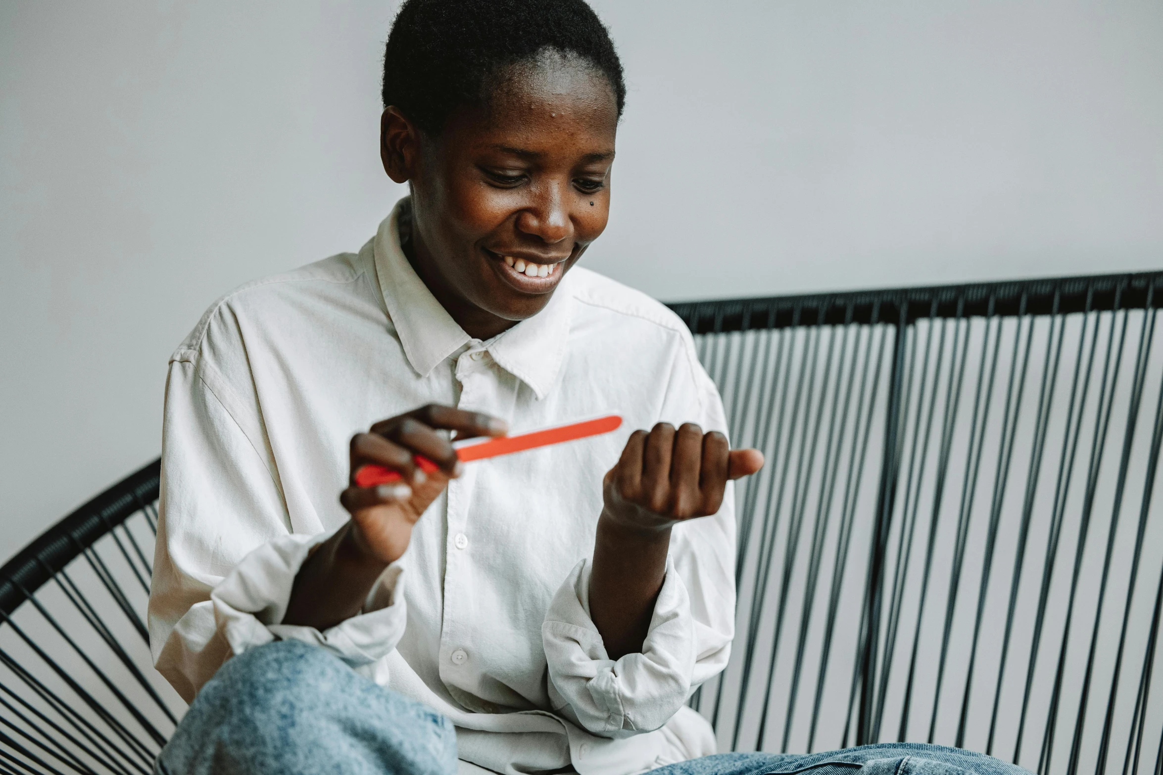 a woman sitting on a white chair playing with a small orange object