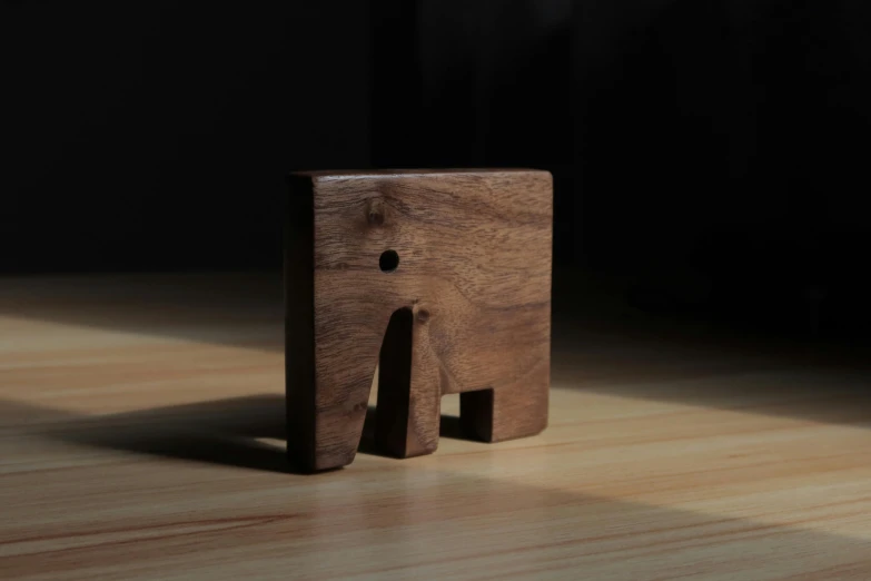 a wooden elephant sitting on top of a hard wood table