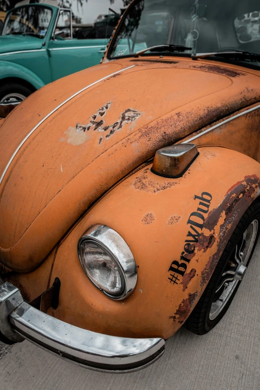 a rusty old vw bug parked on the sidewalk