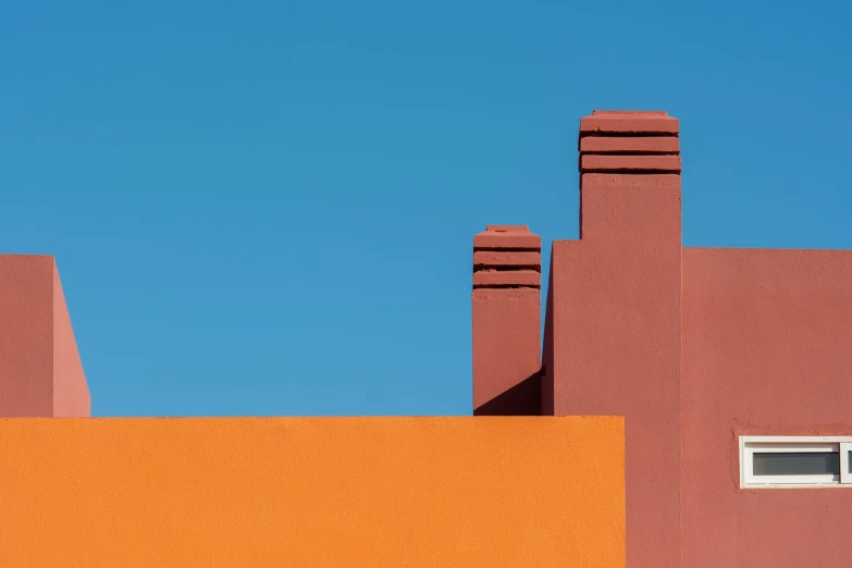 an orange building with two red chimneys and a blue sky