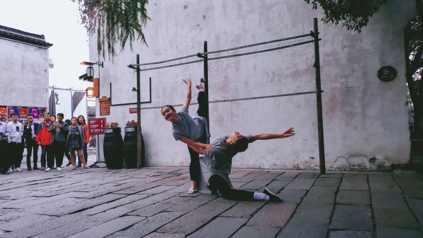 two people are performing a dance on the sidewalk