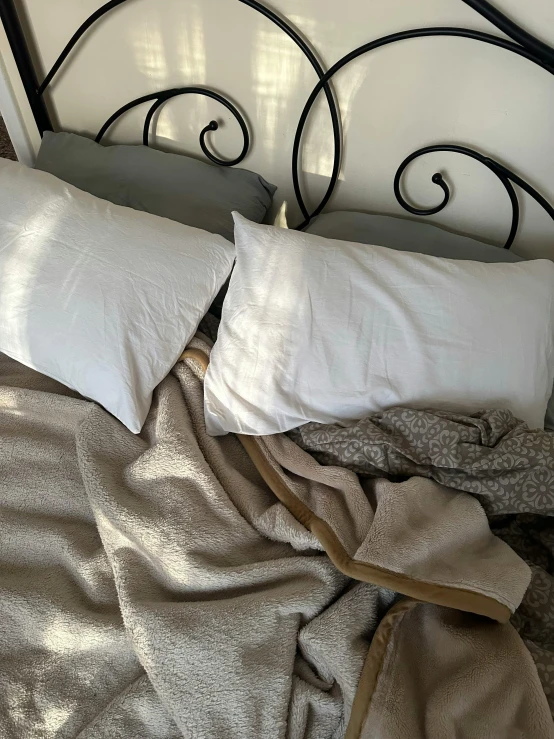 a bed has two pillows and an unmade bed