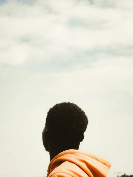 a man wearing an orange towel stands in a field with tall grass