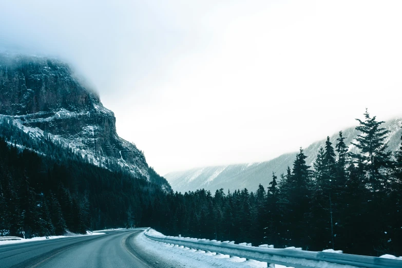 the road is empty with snowy mountains on either side