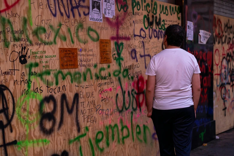 a man stands by a wall covered with messages