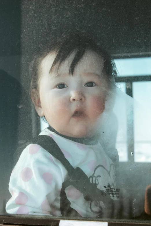 a baby looks out the window of a car as she is seated