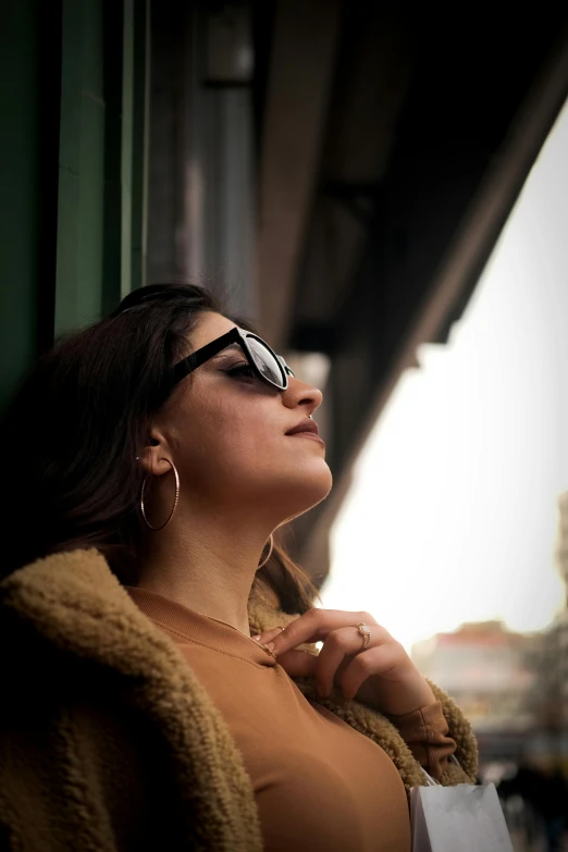 a woman wearing glasses standing next to a green building