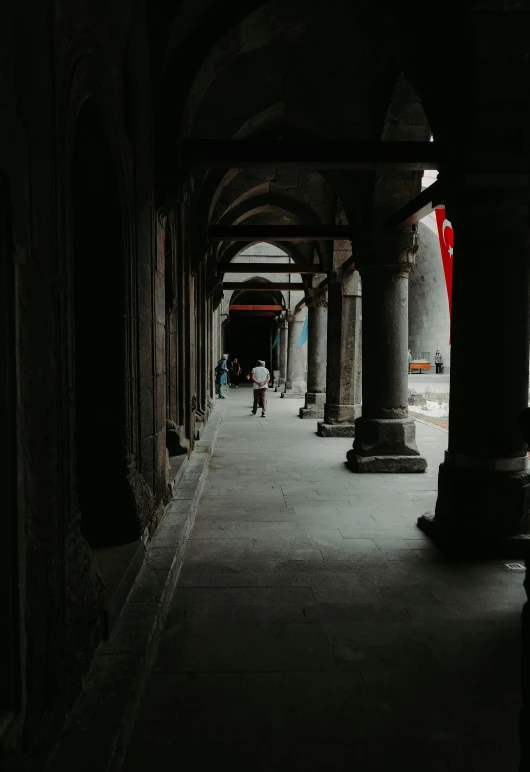 the people are walking under the long row of umbrellas