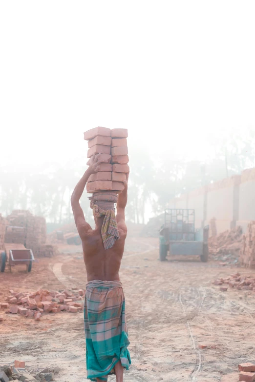 a man carrying bricks on top of his head