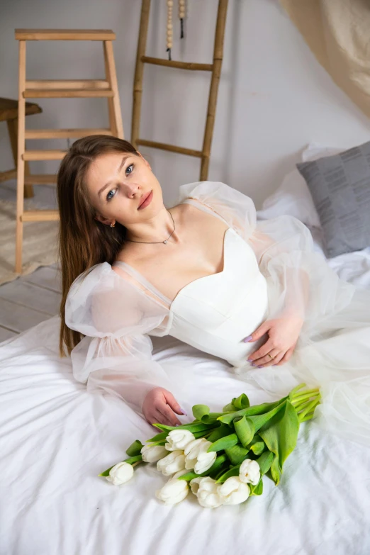 a young woman laying on top of a bed next to a bunch of tulips