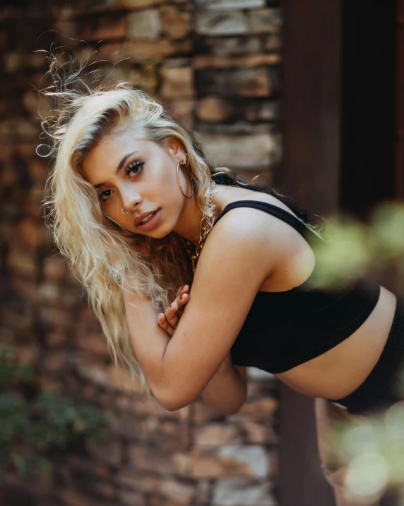 a blonde woman in a black top posing with her arms crossed