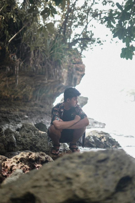 a person sits on some rocks by the water