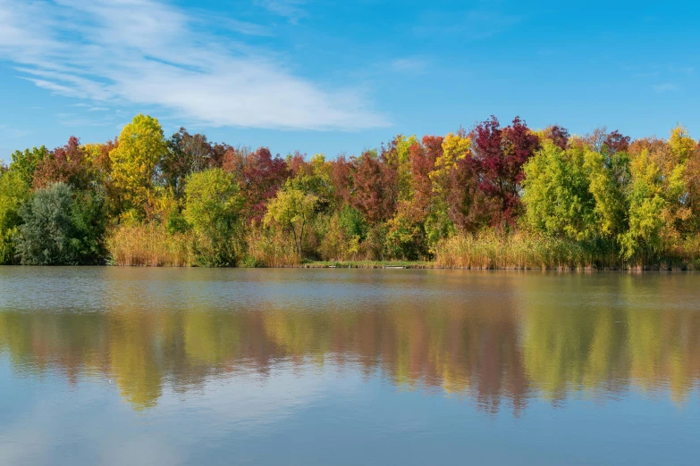 an idyllic lake reflects colorful trees and clouds