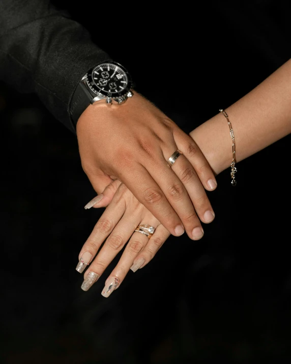 a woman holding another person's hand with multiple rings on it