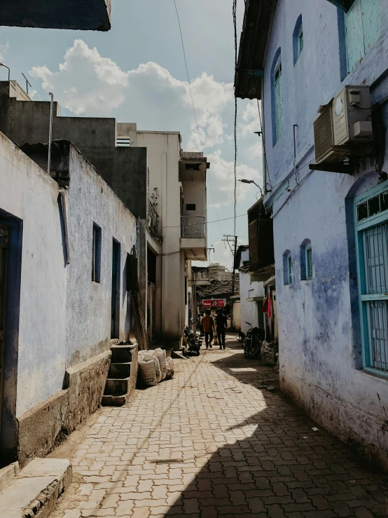 a cobblestone sidewalk next to white buildings with blue windows