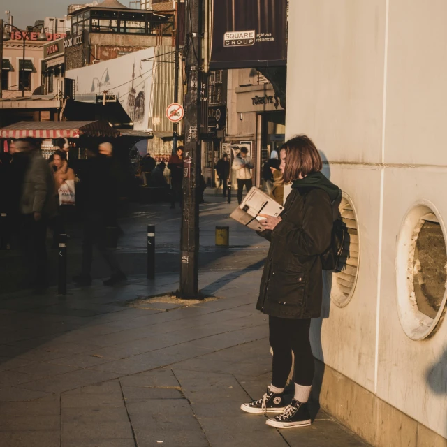 a person reading a magazine on a city sidewalk