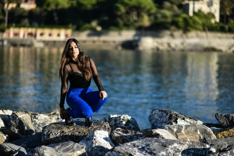 a woman standing by a lake on some rocks