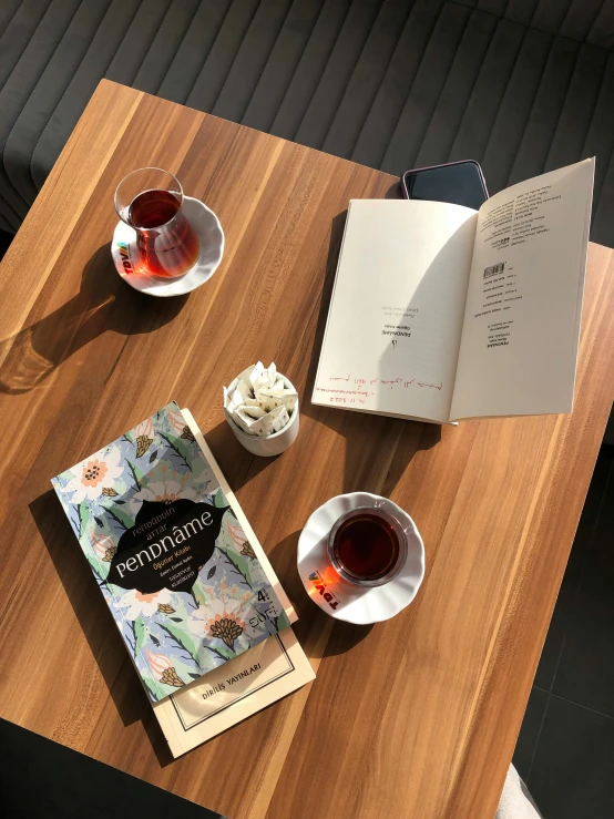 books, tea cups and notebooks are on the wooden table