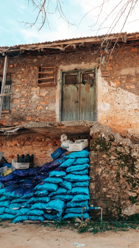 a very old and dilapidated building that has many bags piled on top